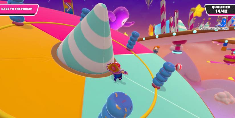 a fall guy bean in a flower hat running on a tilting platform with blue, rubber pylons rotating around it