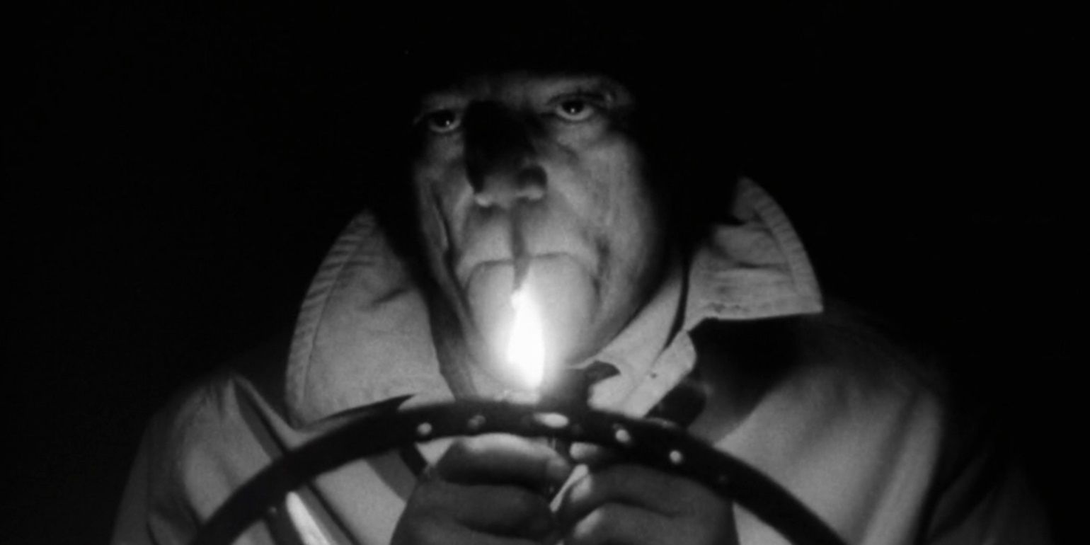 Lemmy Caution lights a cigarette in a car in Alphaville