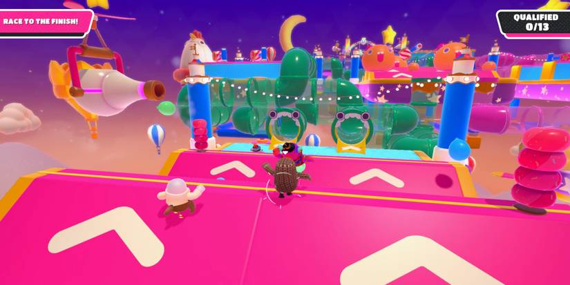 fall guy beans running over pink ramps with beige arrows and rubber pylons at the top