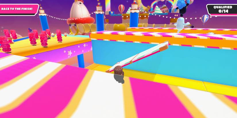 a fall guy bean in brown cloth standing in front of a teetering platform and on another platform in the background is another trap with spinning rubber, pylons