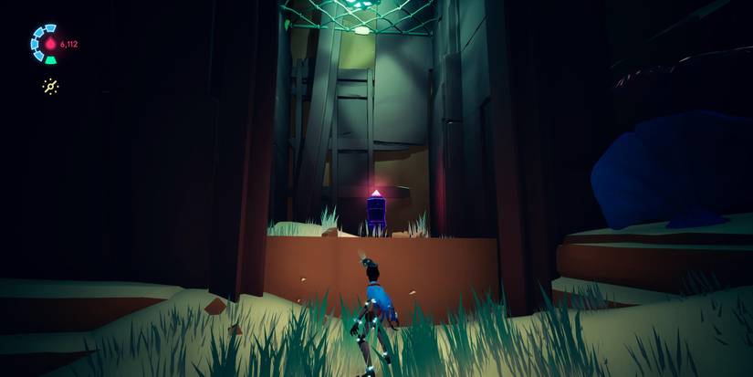 rei standing in a cave with grass on the ground with a cache resting in an alcove up ahead