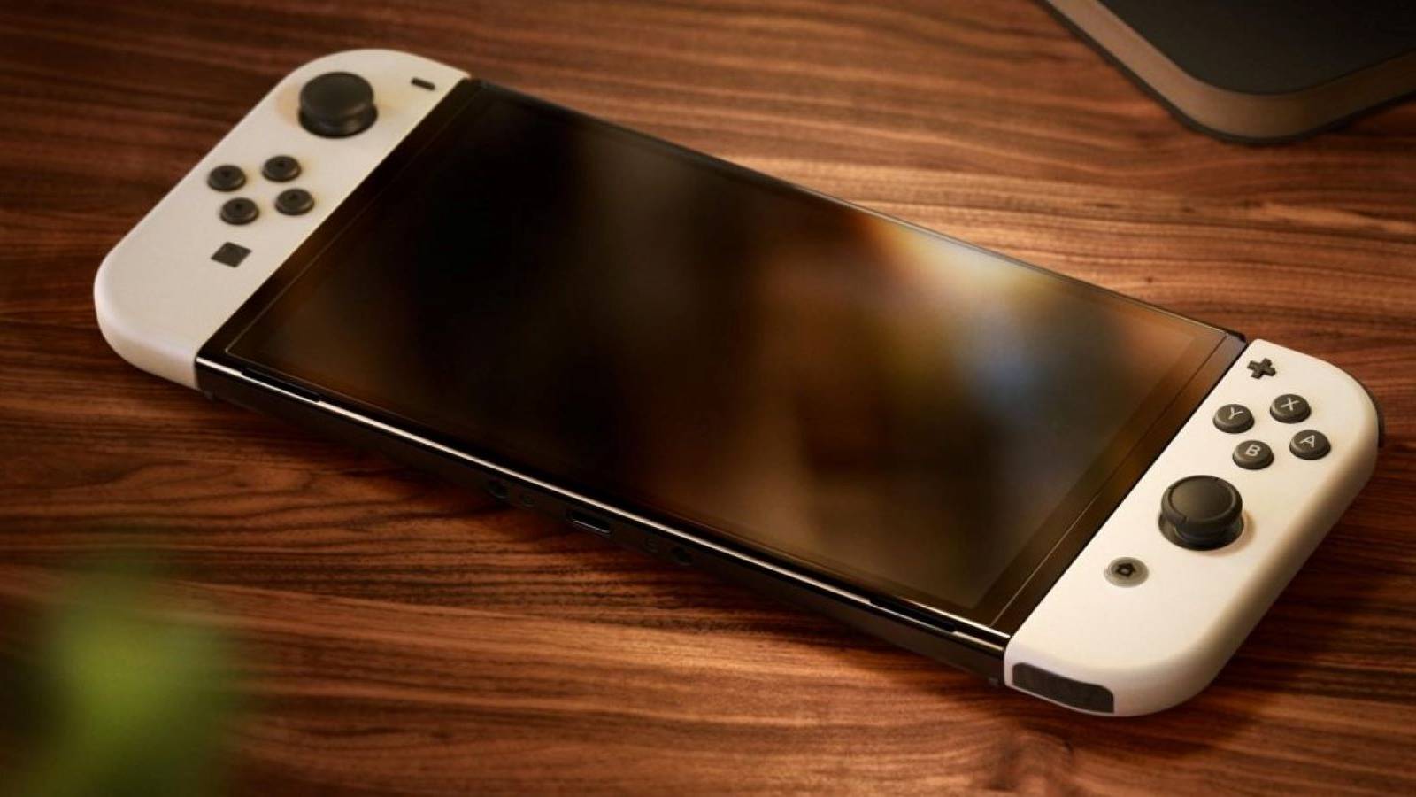 A Nintendo Switch OLED with white Joy-Cons laying on a table