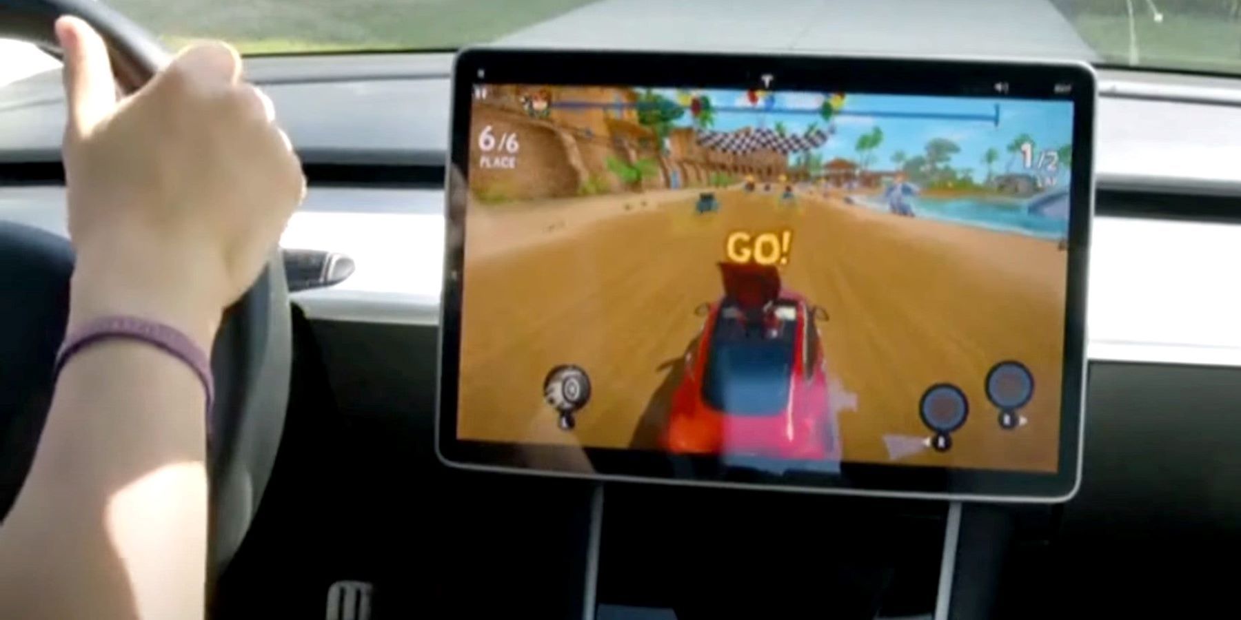 A Tesla owner driving a vehicle while a racing video game plays on the center screen