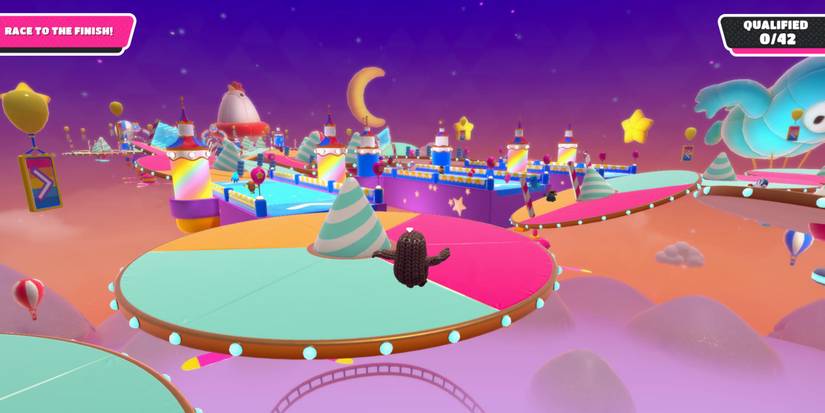 a fall guy bouncing into the air toward a colorful, round platform with a striped cone in the middle