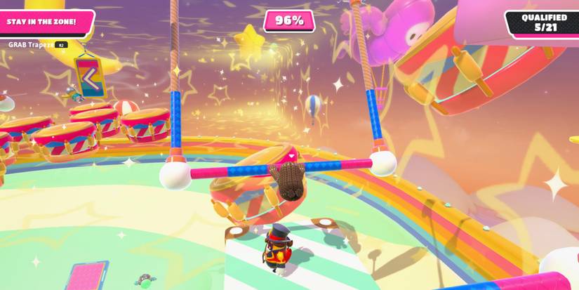 a fall guy bean swinging from a trapeze bar over a green and white striped platform