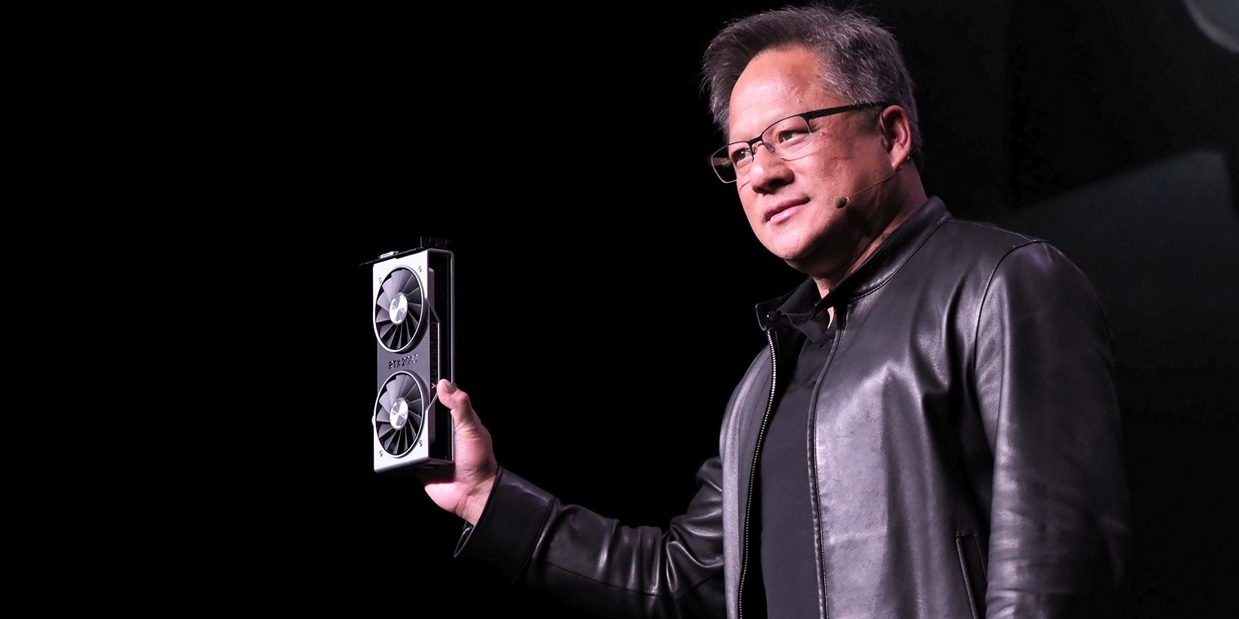 Photo of Nvidia CEO Jensen Huang holding up an RTX graphics card.