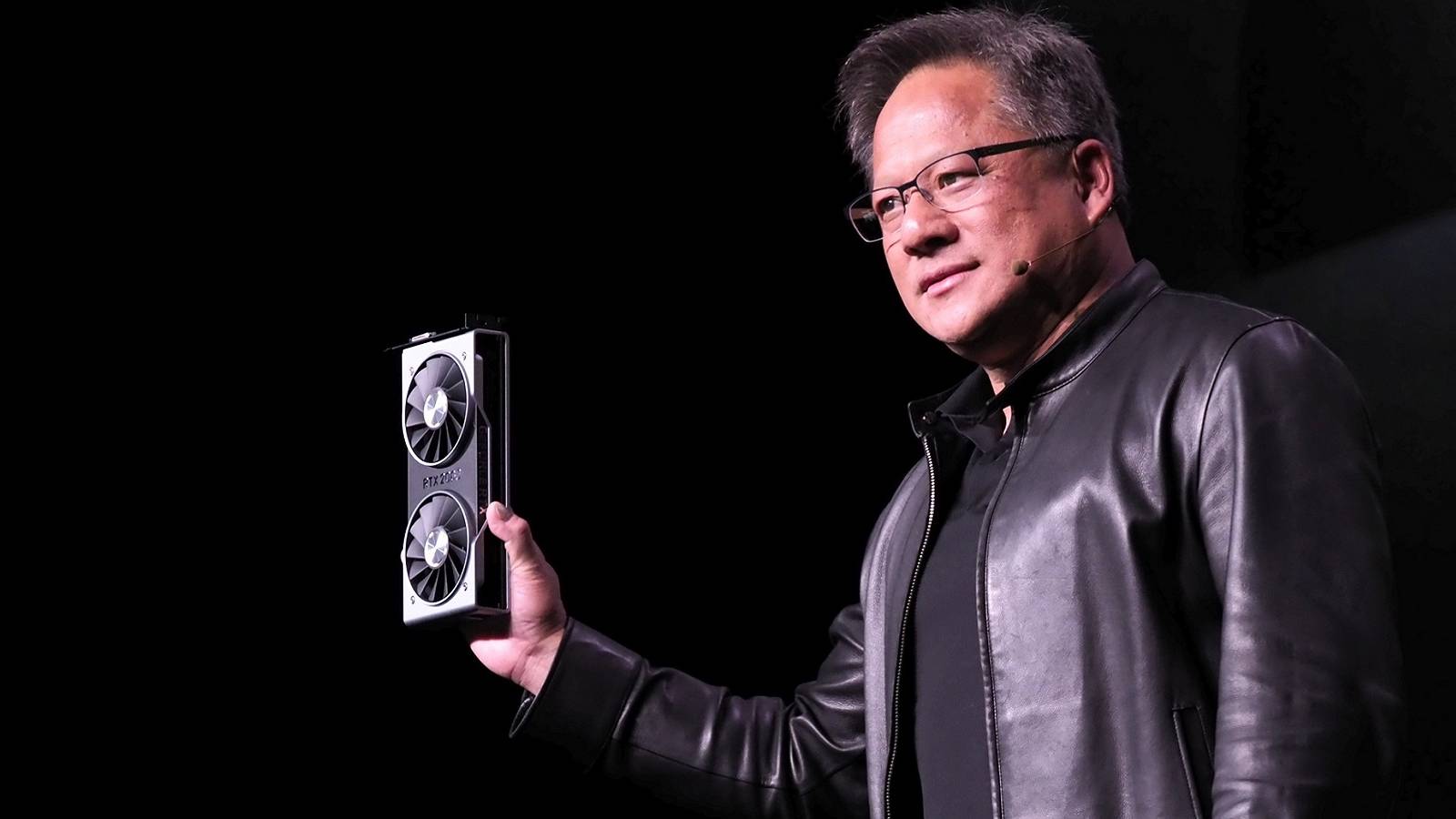 Photo of Nvidia CEO Jensen Huang holding up an RTX graphics card.