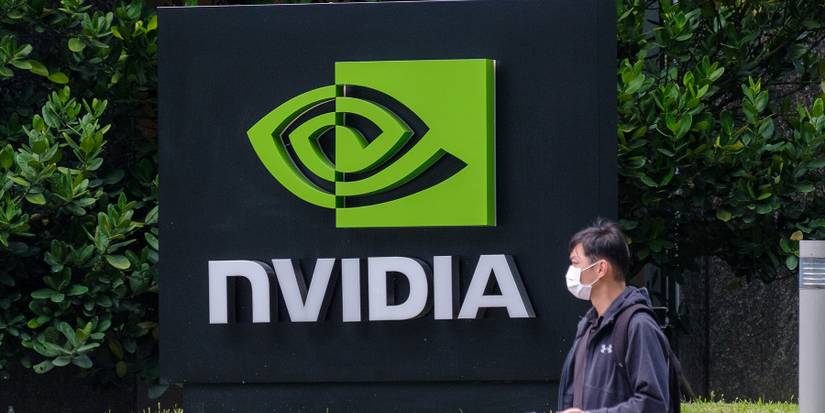 A photo of the Nvidia logo outside its building as a man wearing a face mask walks past.