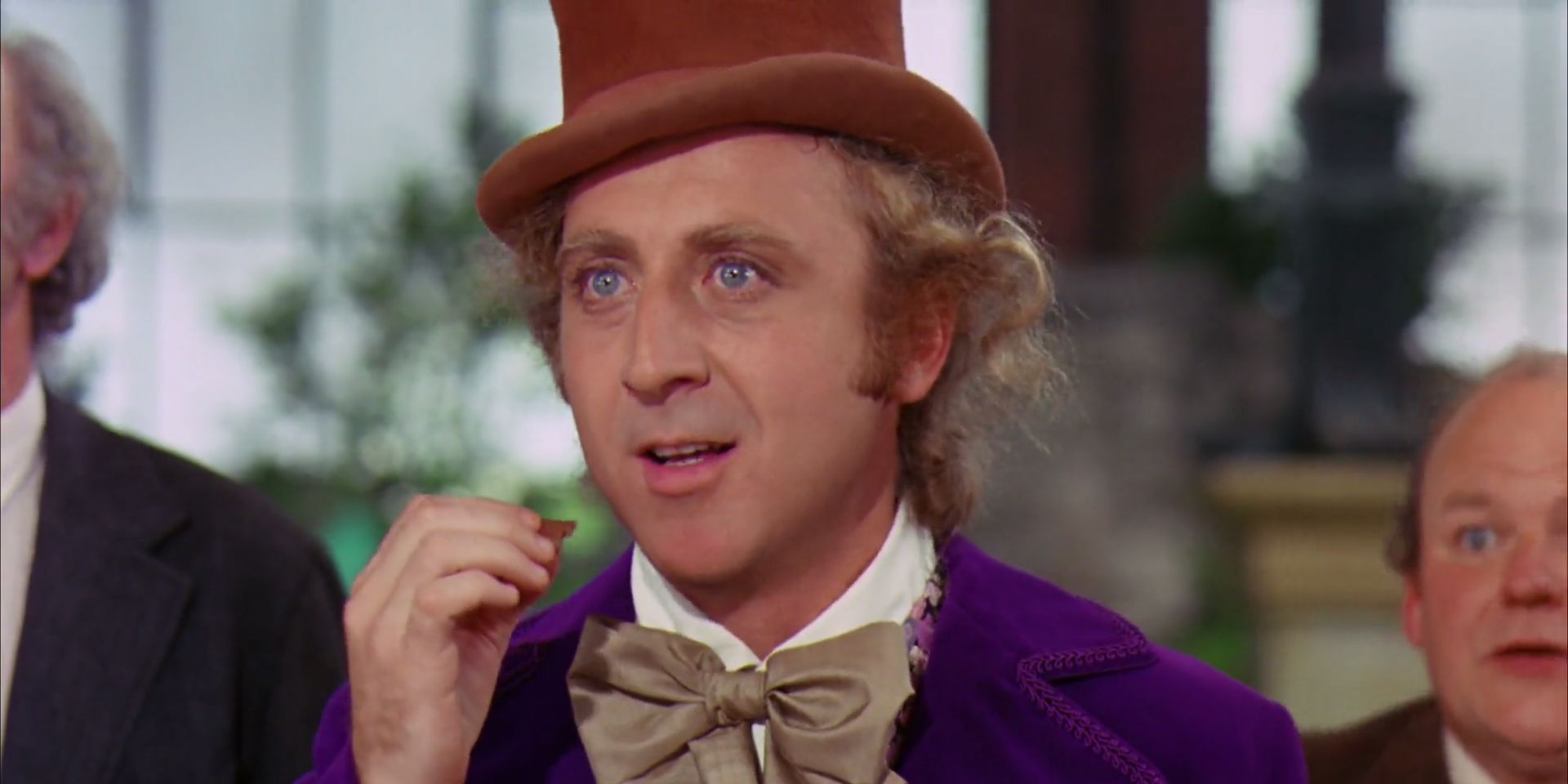 Gene Wilder as Willy Wonka, wearing his signature hat and bowtie, stands in his chocolate factory