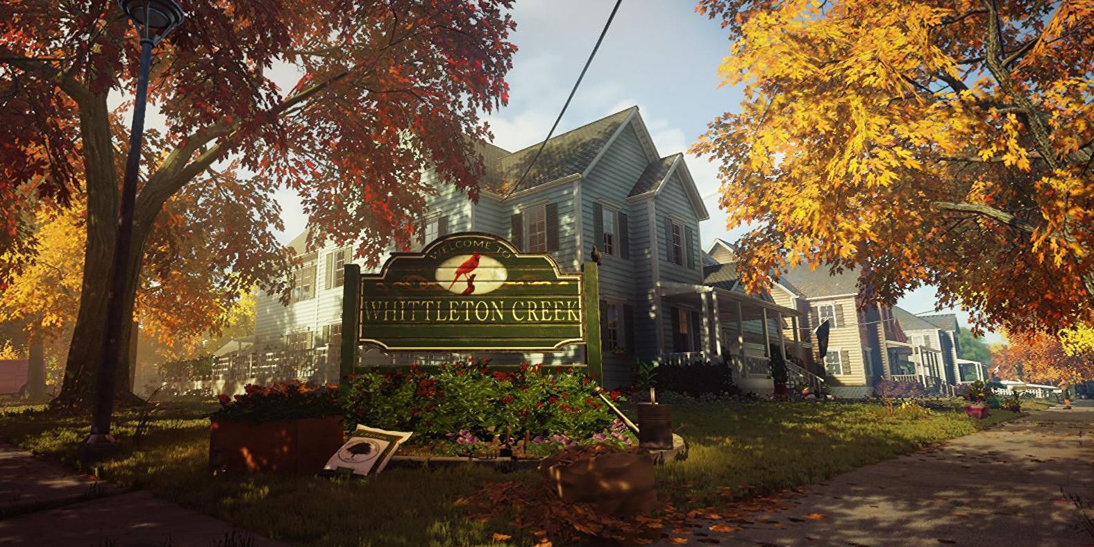 The town of Whittleton Creek in Hitman 2. Trees with autumn leaves border a blue house.