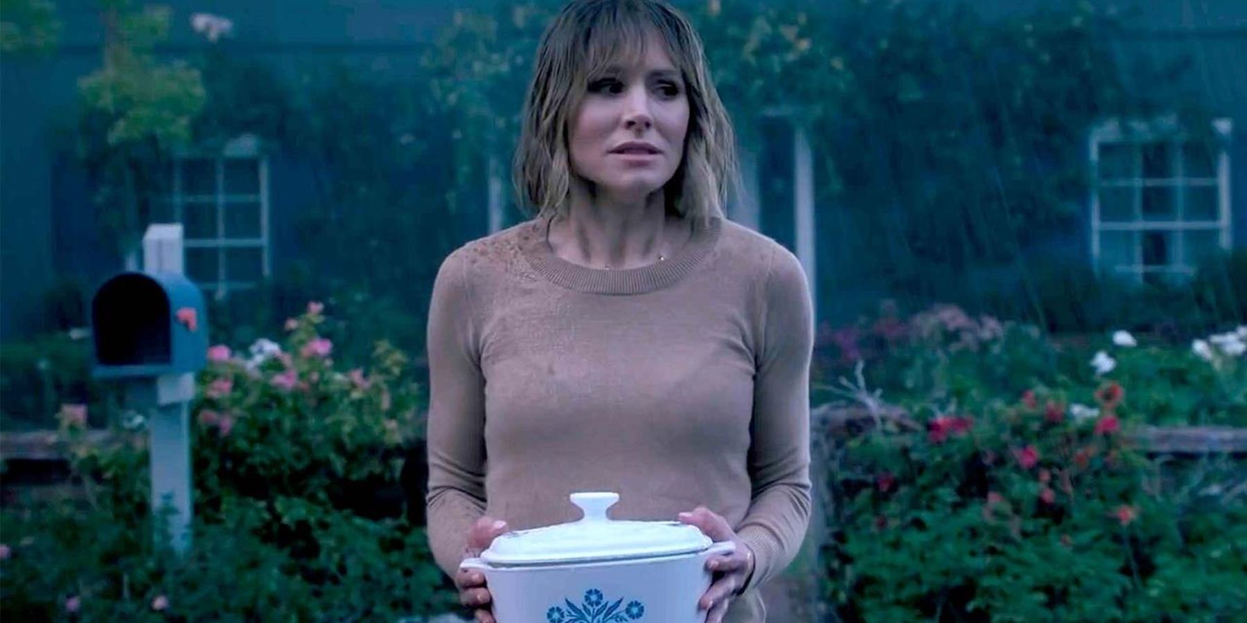 Kristen Bell holding a casserole dish in the rain in The Woman in the House Across the Street from the Girl in the Window