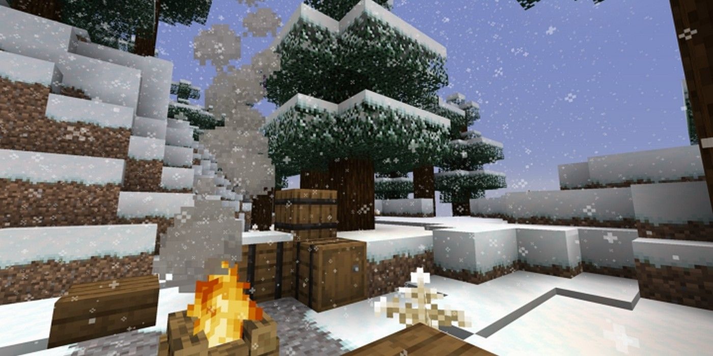 zonă pitorească înzăpezită lângă munte acoperit de zăpadă, copac și foc de tabără în Minecraft