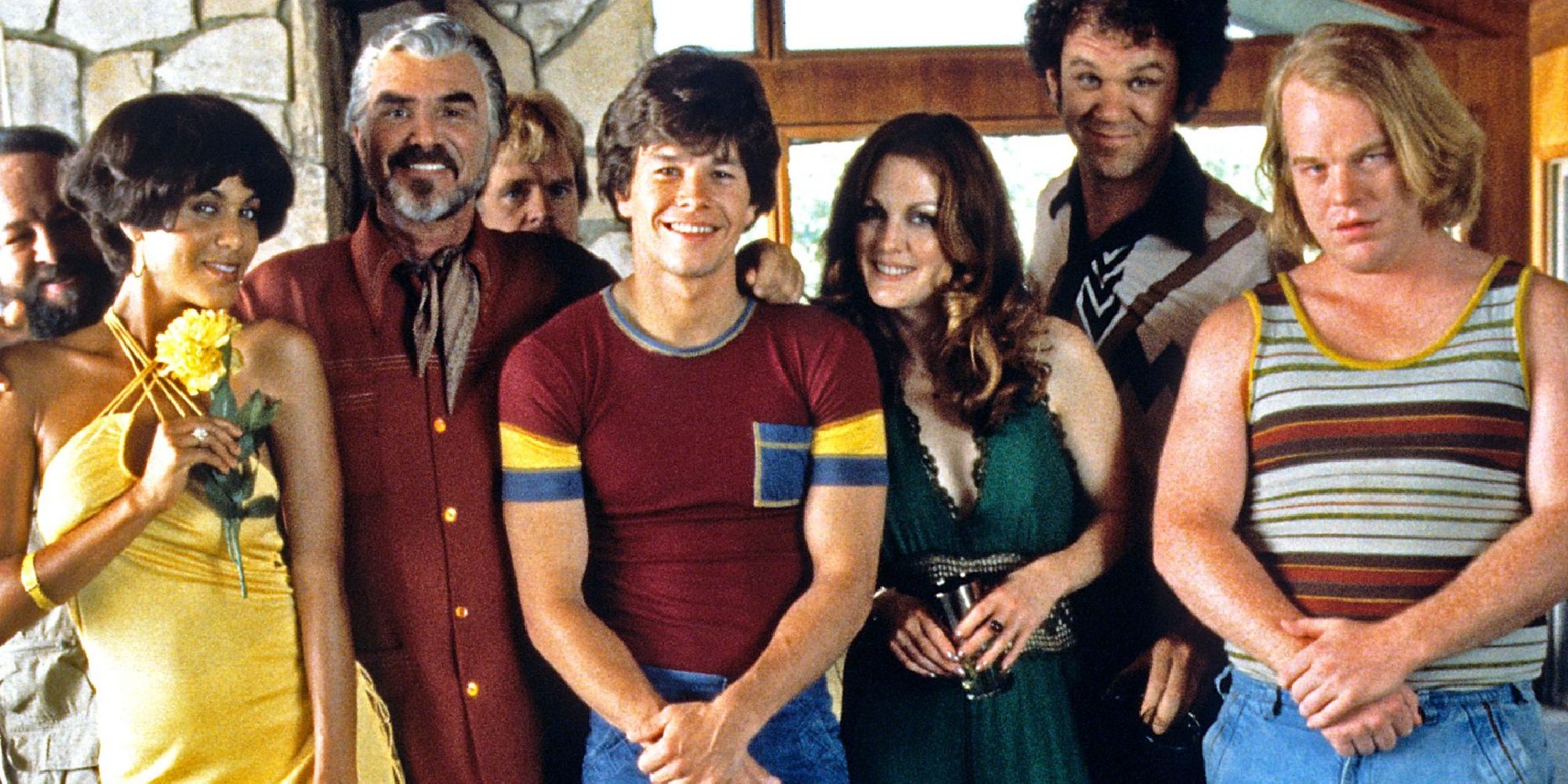 Marh Wahlberg, Burt Reynolds, Philip Seymour Hoffman, John C. Reilly, Julianne Moore, and Nicole Ari Parker posing for a photo together in Boogie Night