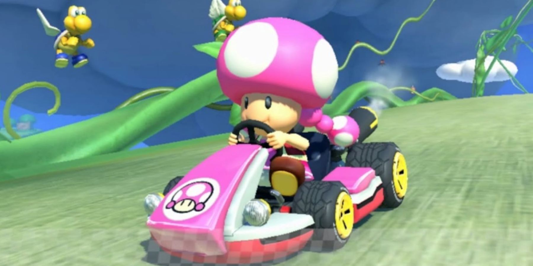 Toadette driving a kart in Mario Kart Wii with two Koopa Paratroopas in the background