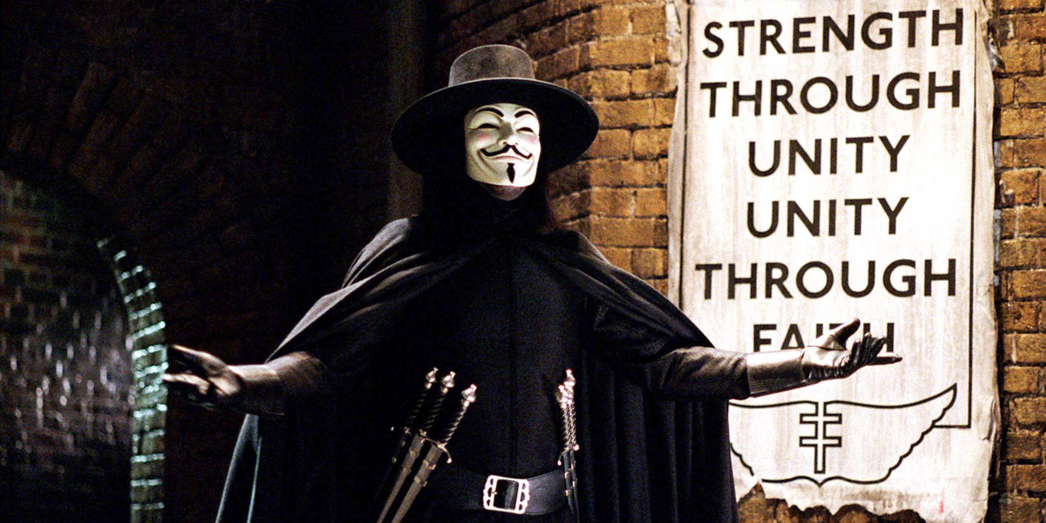 Ви, которого играет Хьюго Уивинг, одетый в маску Гая Фокса и с ножами, стоит в переулке в фильме «V — значит Вендетта».