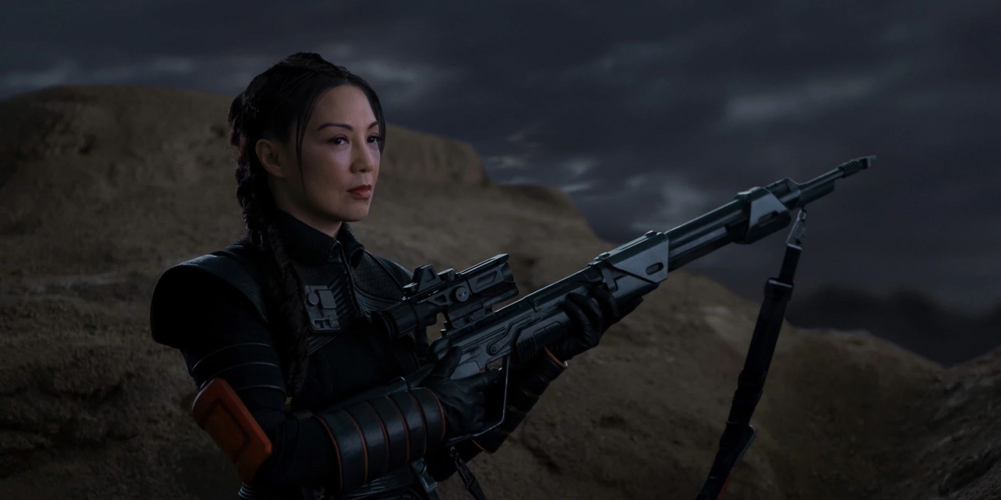 An image of Fennec Shand from TV show The Mandalorian holding a sniper rifle.