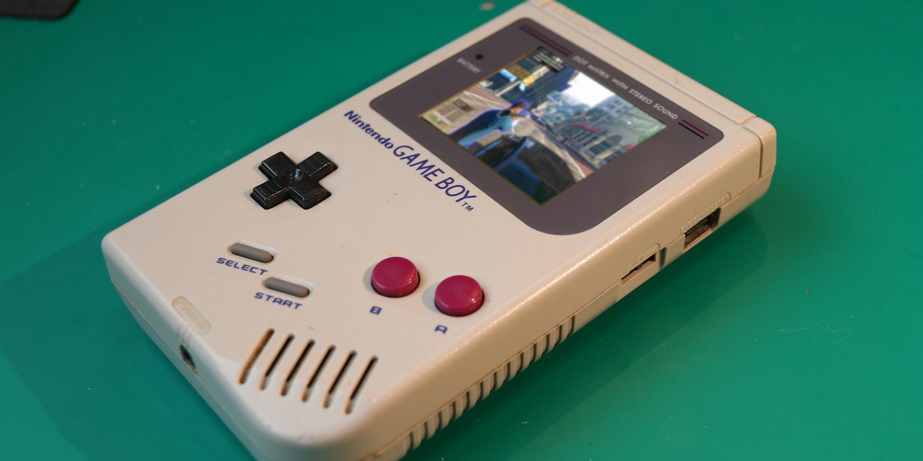 Une photo d'une Nintendo Game Boy avec une capture d'écran de Grand Theft Auto 5 superposée à l'écran.