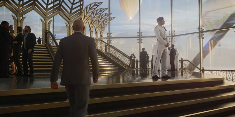 An image from Hitman 3 showing Agent 47 walking up some fancy stairs.