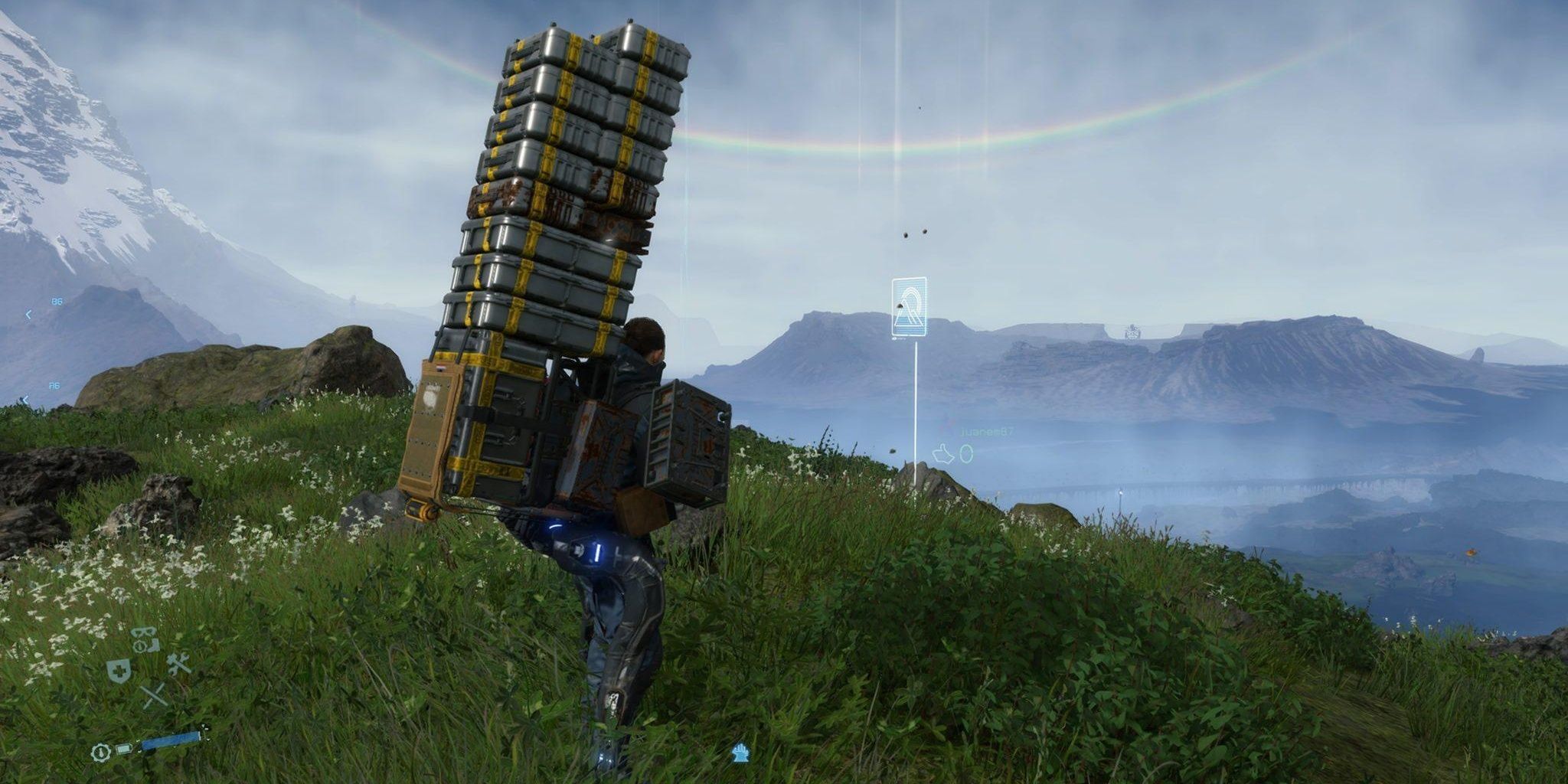 Sam Bridges (Norman Reedus) carries a huge number of boxes and crates on his back in the game Death Stranding. A rainbow is in the background