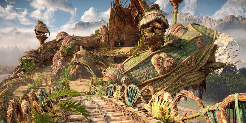 a building made entire of plant material, with green, woven roofs and a wooden walkway leading up to it