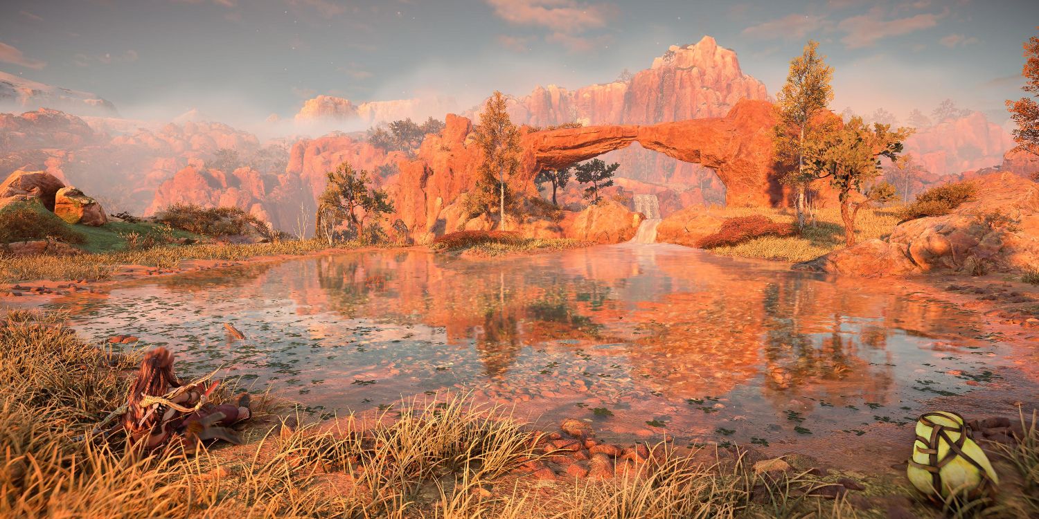 aloy sitting by the side of a shallow lake with a natural stone arch at the other end