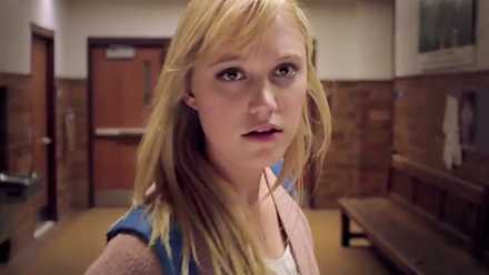 Jay (Myka Monroe) standing in a high school hallway in It Follows.