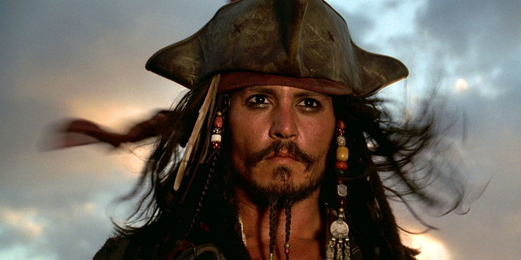 Джек Воробей (Джонни Депп) смотрит на закат с ветром в волосах в фильме «Пираты Карибского моря: Проклятие Черной жемчужины».