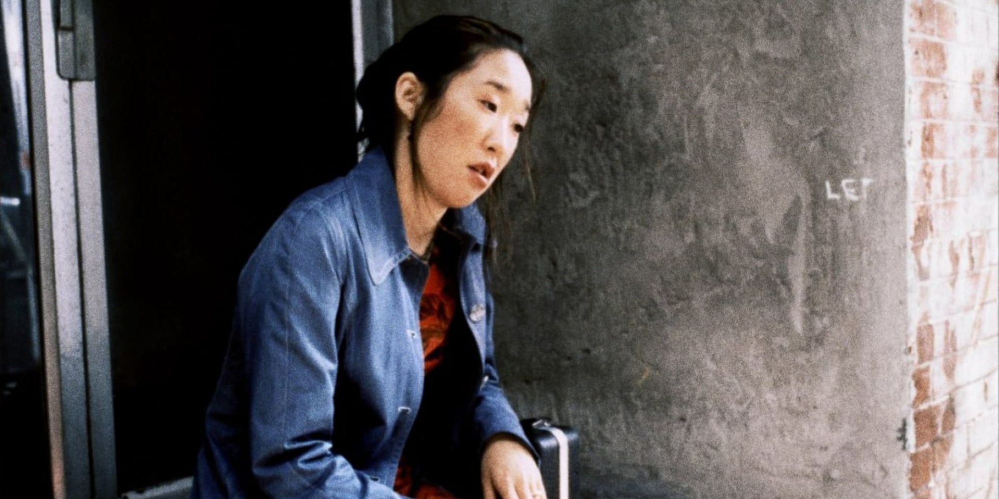 Sandra Oh's character sits on the stoop, looking exhausted in Last Night
