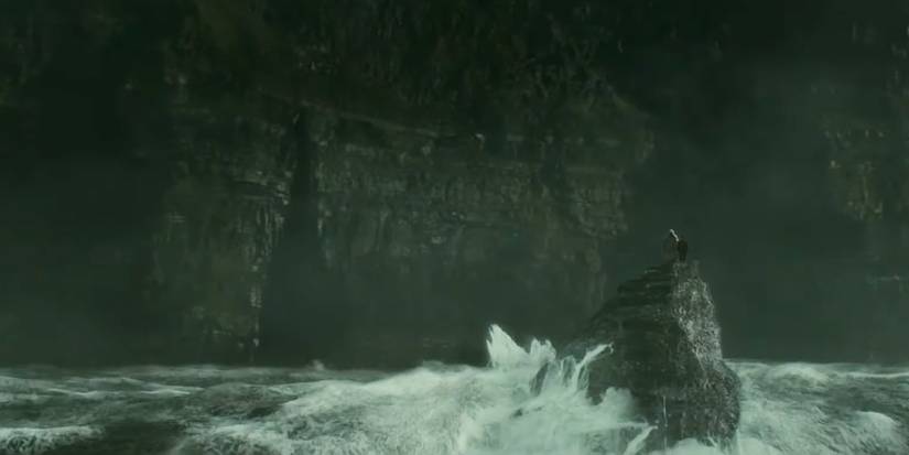 Dumbledore and Harry Potter stand on a rock in a violent sea, with a cave in the Cliffs of Moher ahead of them, in The Half-Blood Prince.