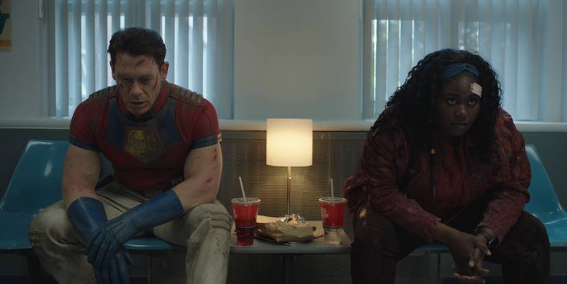 Peacemaker and Adebayo sitting in a hospital waiting room in Peacemaker