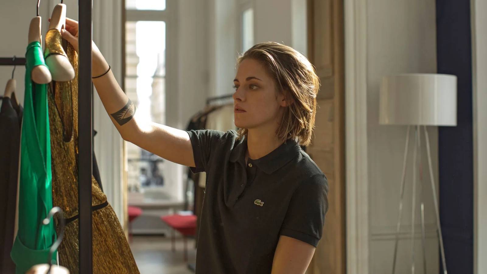 Kristen Stewart as Maureen holding up clothes in Personal Shopper