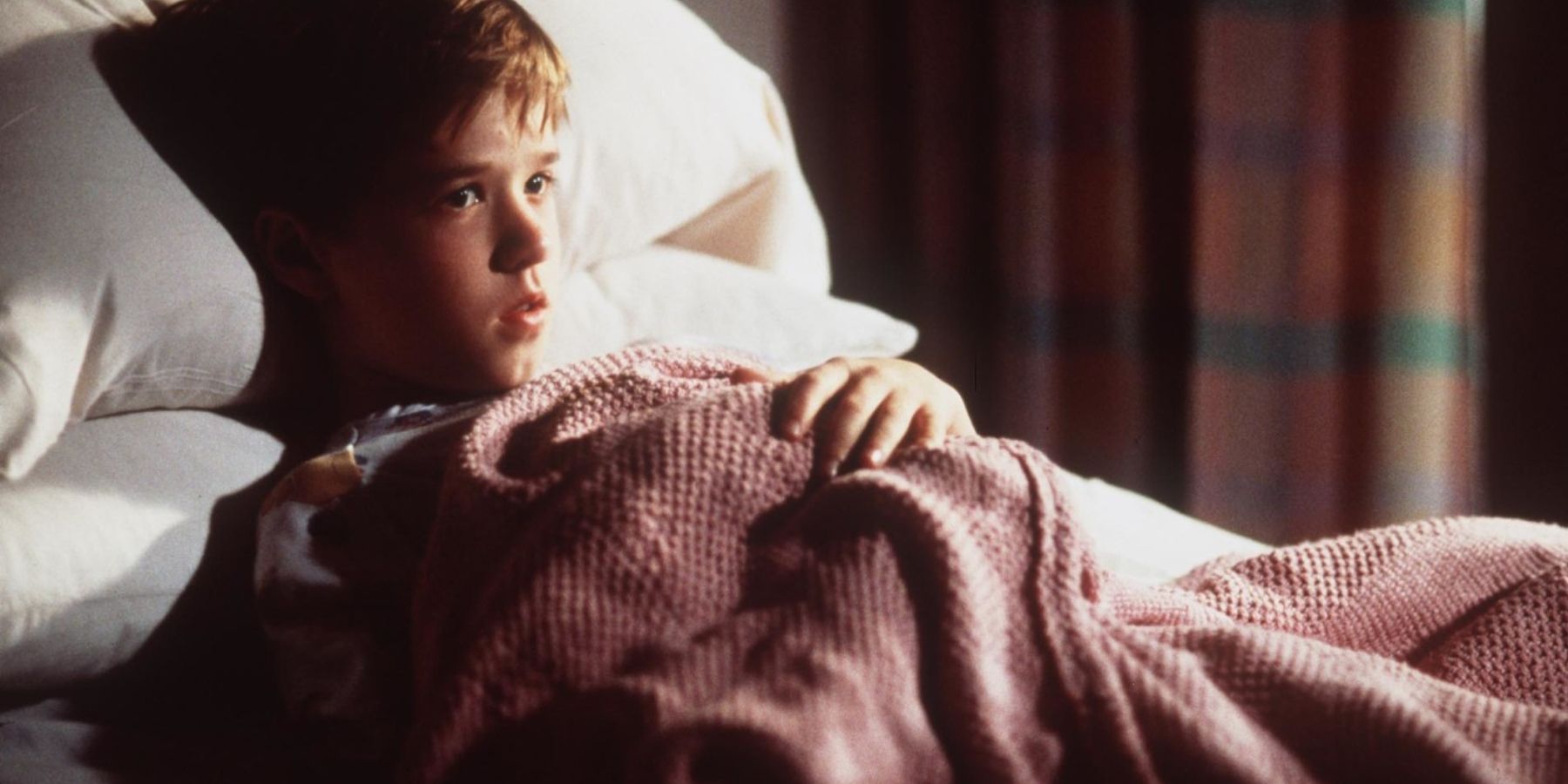 Haley Joel Osment as Cole lying in bed under blankets in The Sixth Sense