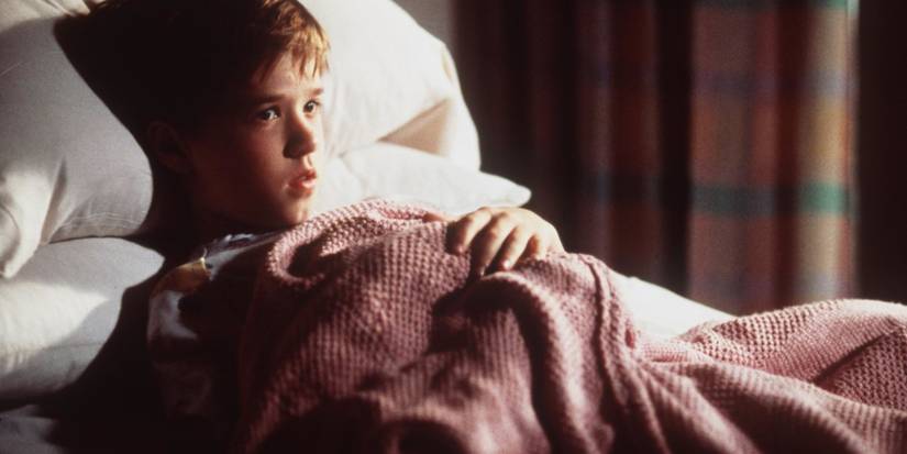 Haley Joel Osment as Cole lying in bed under blankets in The Sixth Sense
