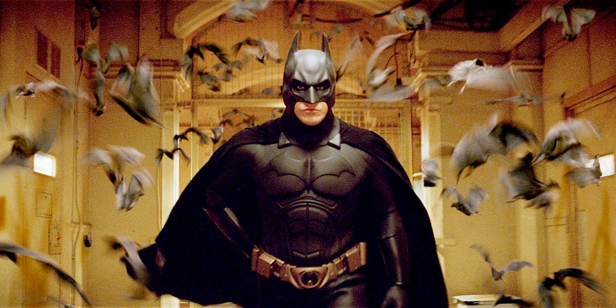 Christian Bale's Batman running through a hallway with a swarm of bats in Batman Begins
