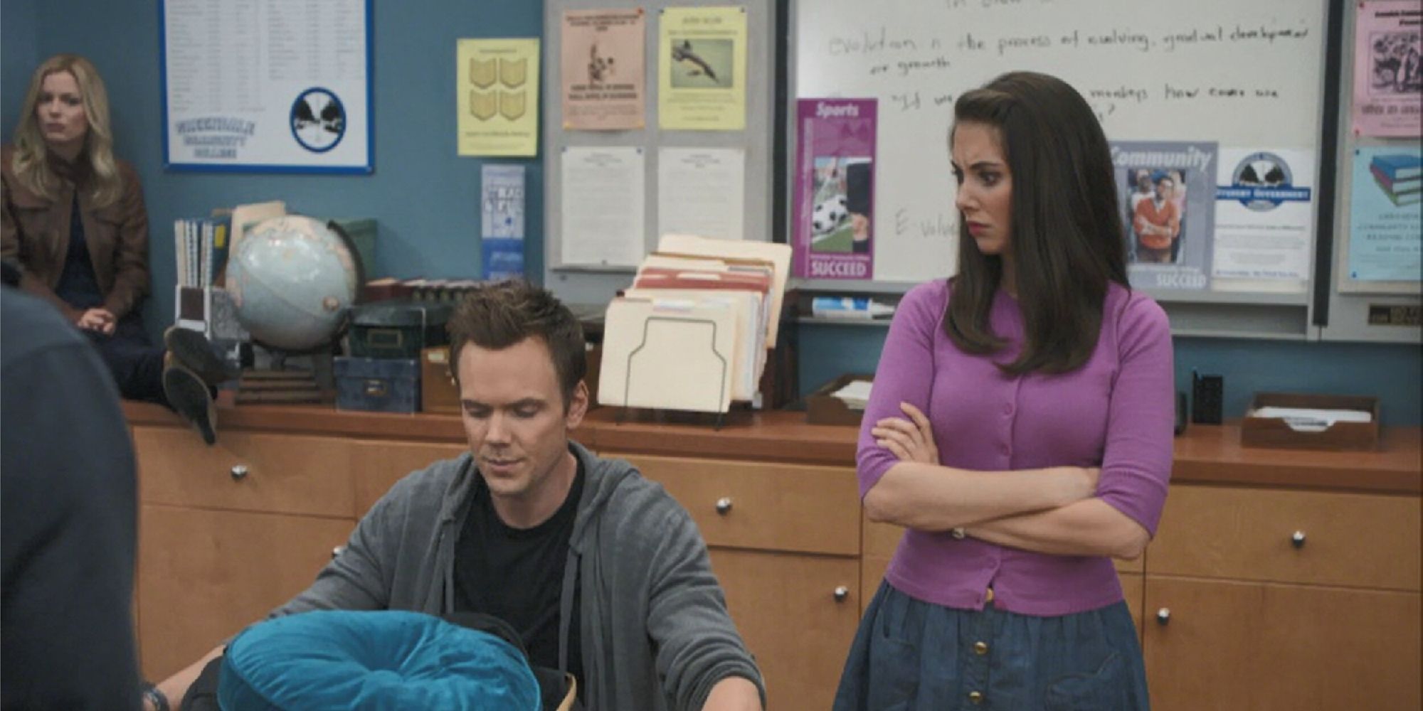 Annie and Britta watching as Jeff inspects Troy's bag in "Cooperative Calligraphy"