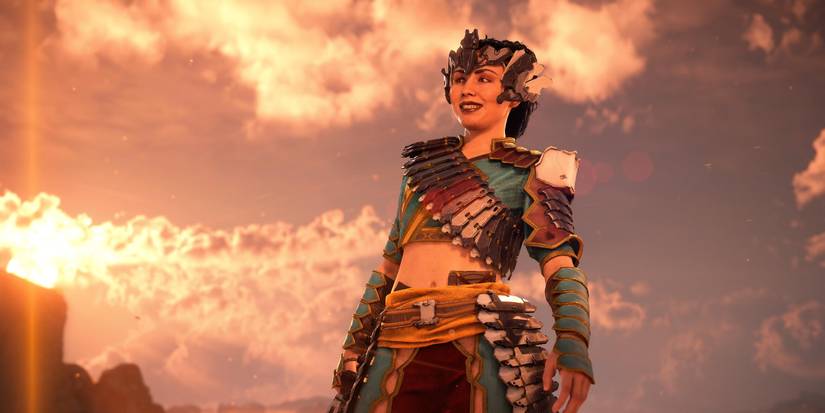 talanah in her metal, feather armor and headdress smiling with her back to a blue sky with the sun setting on the left