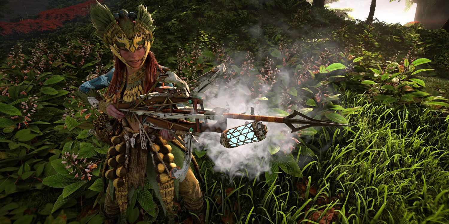 Aloy in a green and yellow outfit with an ornate headdress holding a spear gun with a light blue canister attached to the shaft 