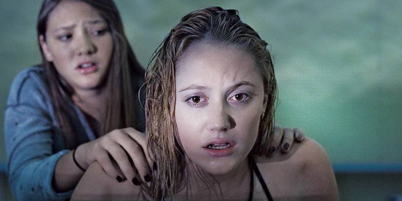 Maika Monroe staring at something from a poolside in It Follows