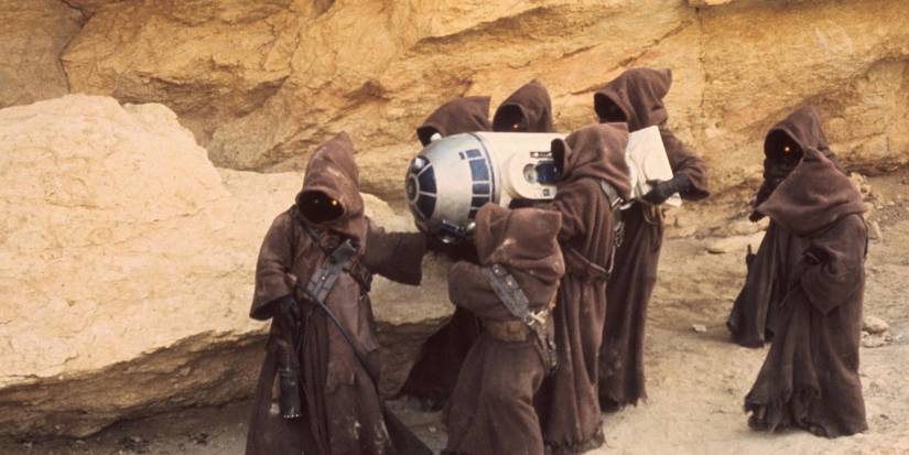 Star Wars Jawas carrying R2 D2 on side in rocky Tatoonie desert