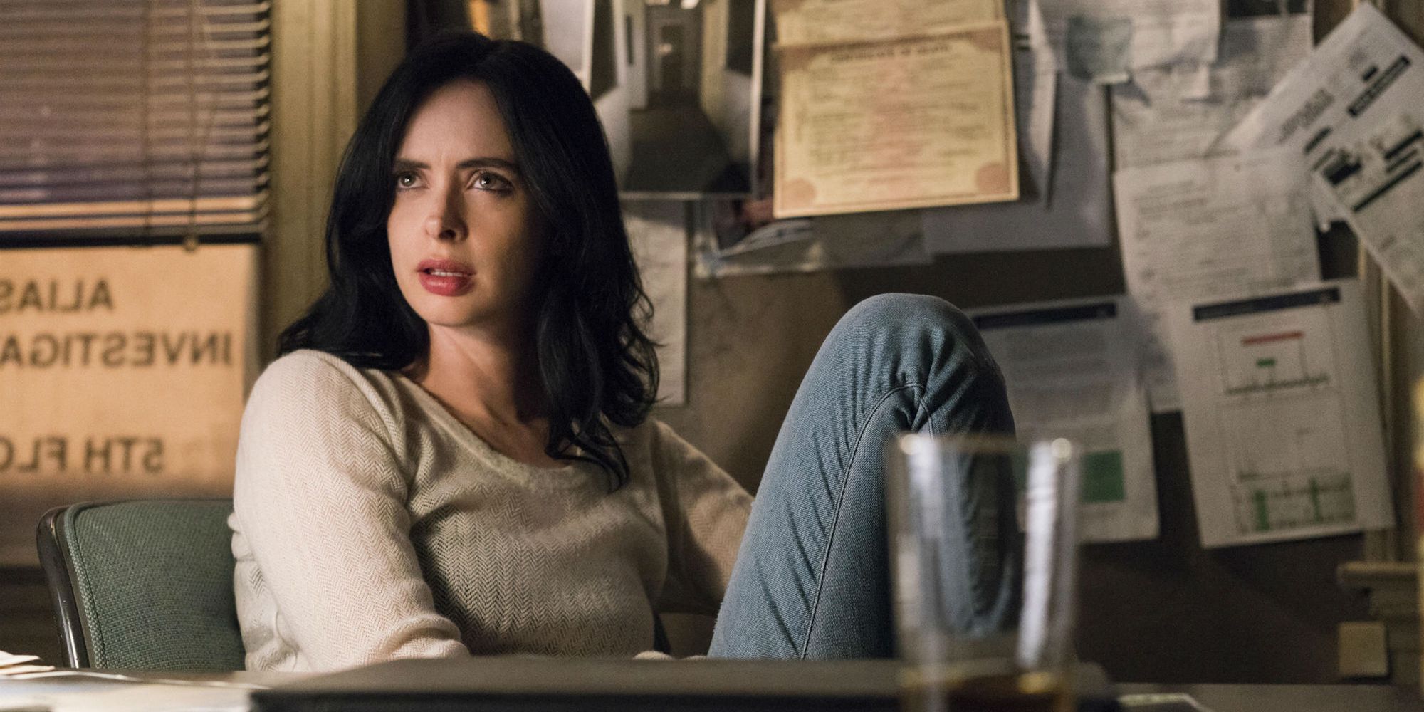 Krysten Ritter as Jessica Jones sitting at her desk