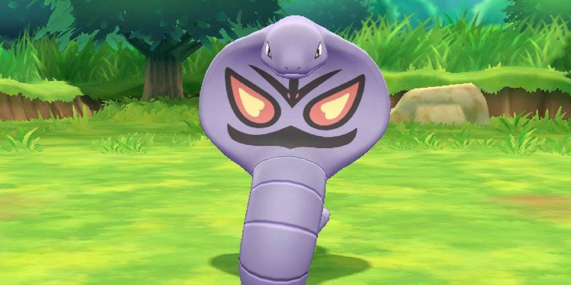 Arbok appearing in a grassy field in Pokemon Let's Go