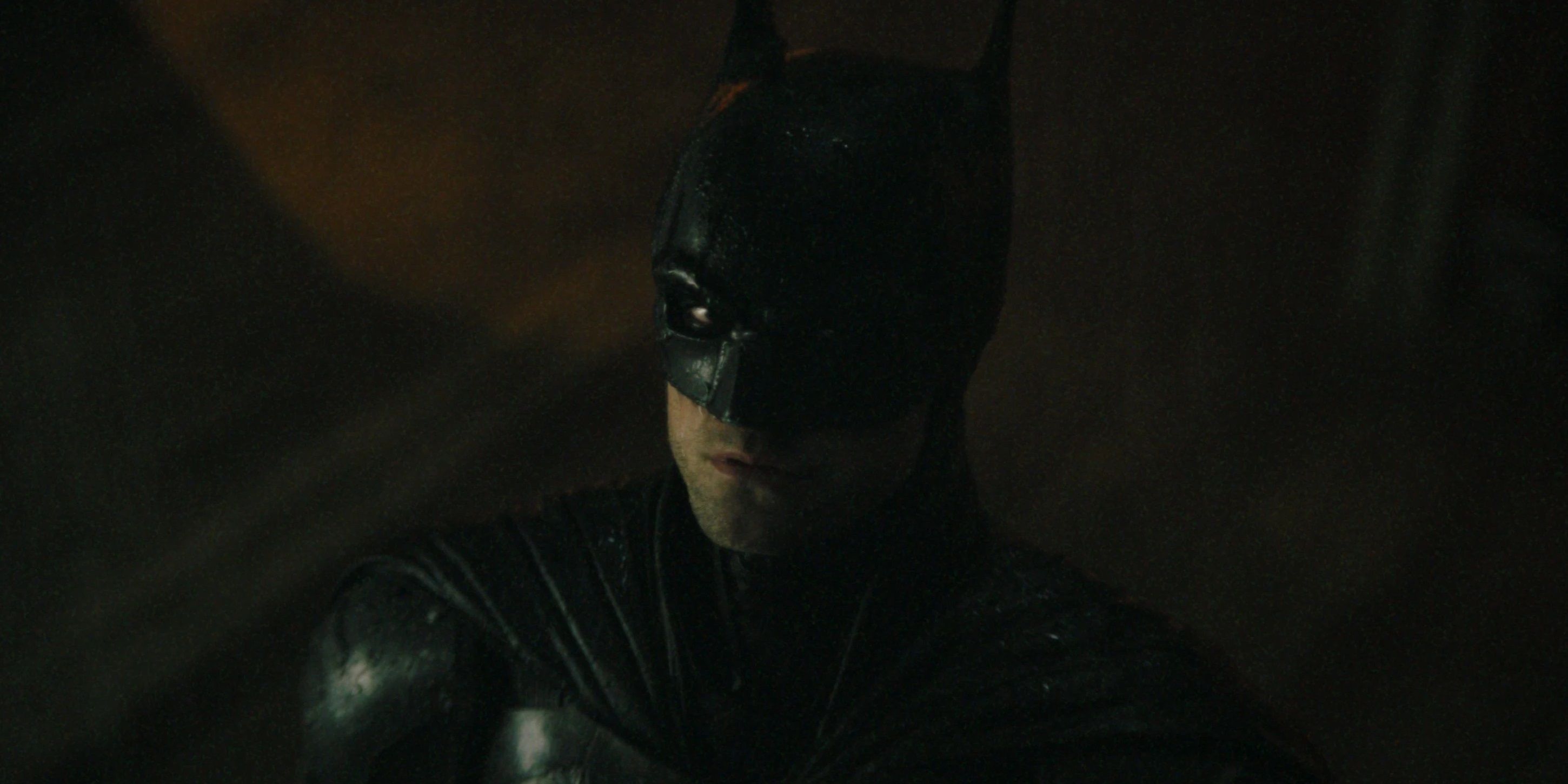 Robert Pattinson as Batman looking up in the rain