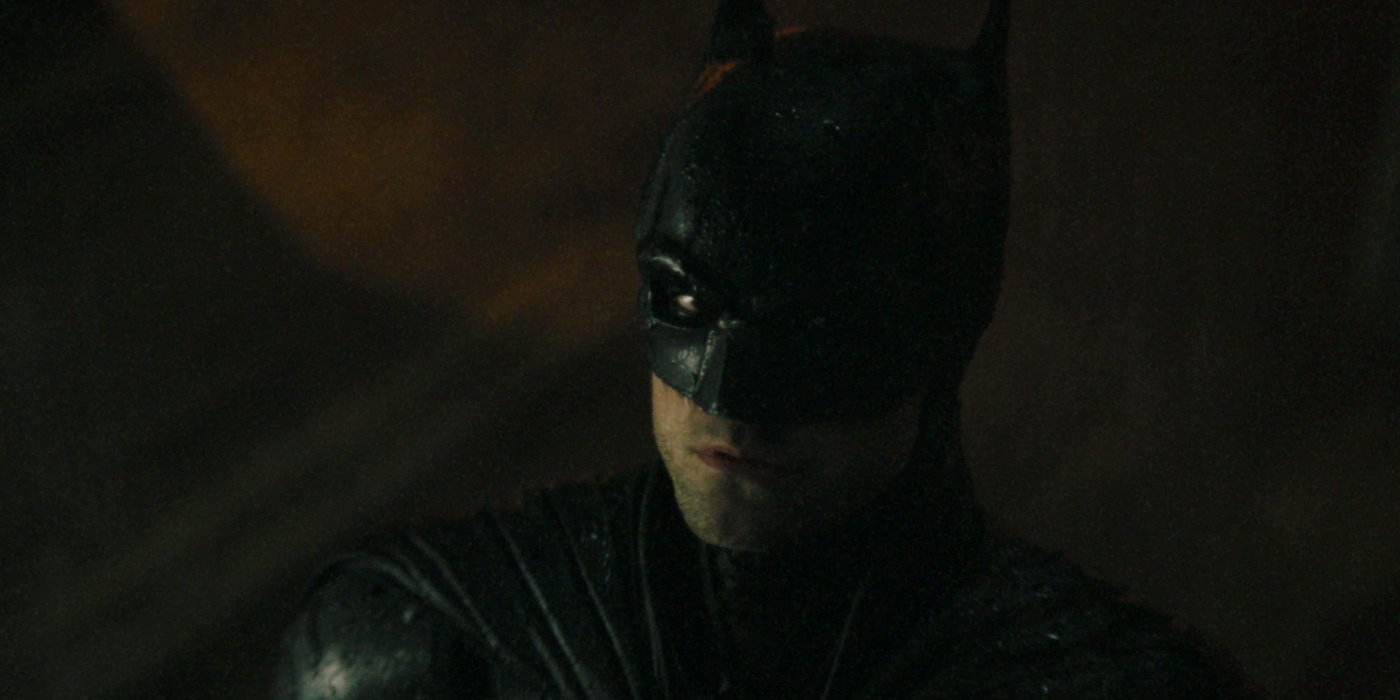 Robert Pattinson in the Batsuit looking up in the rain in The Batman