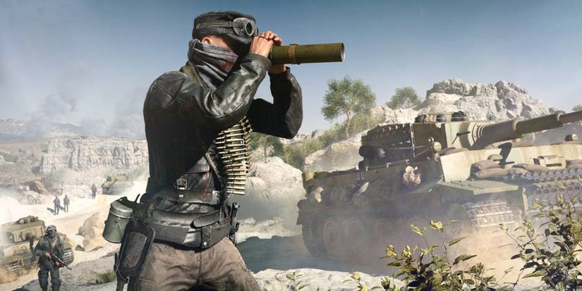 A Recon player uses the spotting scope in Battlefield 5, with a tank in the background.