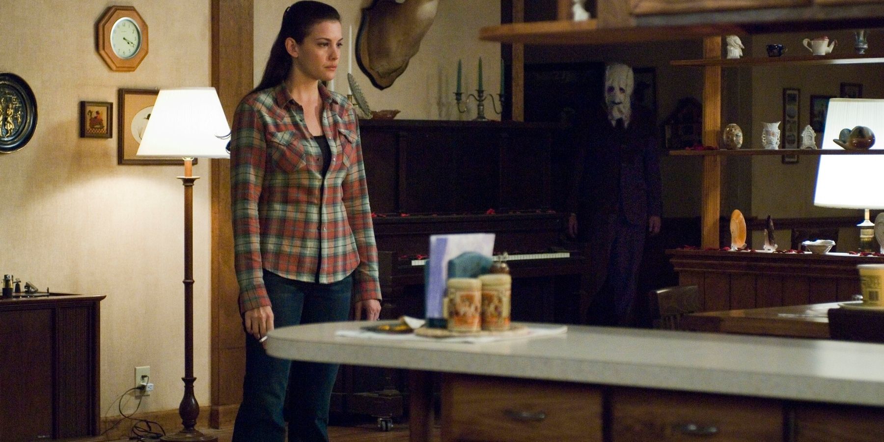 Kristen (Liv Tyler) standing in the house looking serious in The Strangers