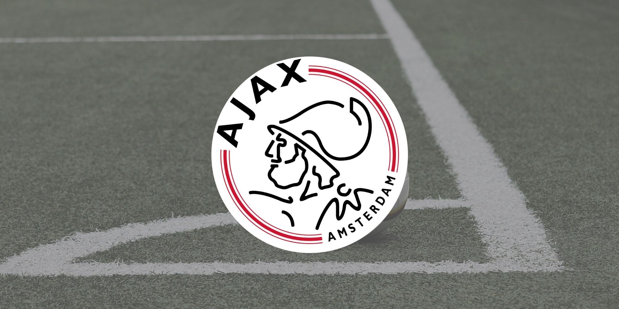 The official Ajax club badge over an image of a football field.