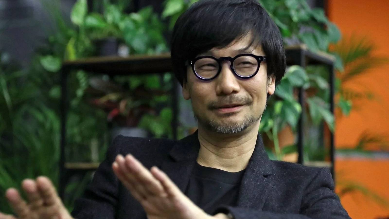 Photo of Hideo Kojima with plants in the background.