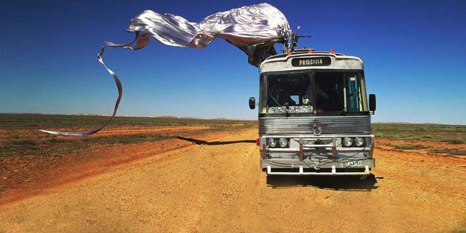The Adventures of Priscilla, Queen of the Desert promo photo bus in the desert with silver banner on top