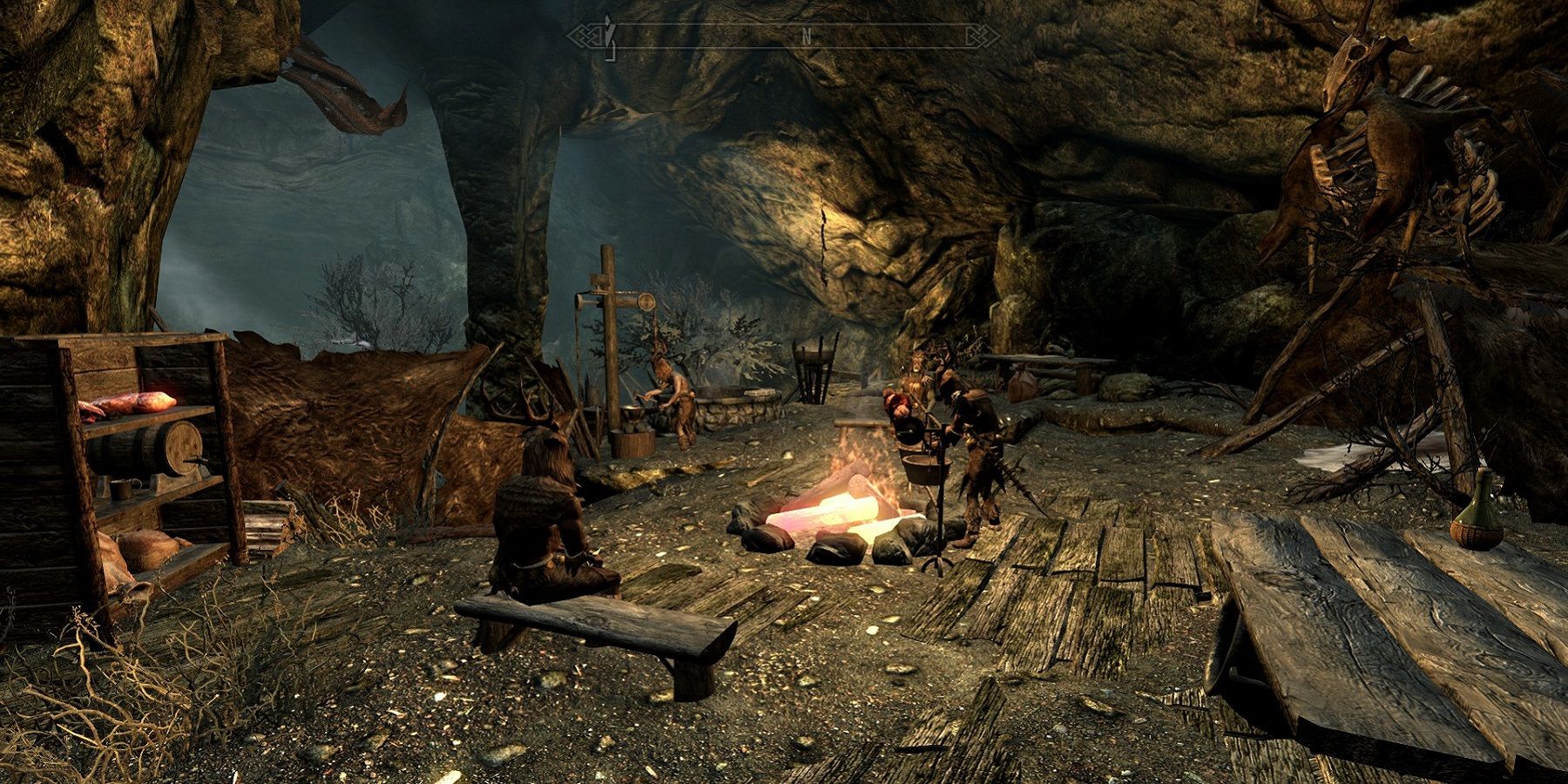 Screenshot from The Elder Scrolls 5: Skyrim showing bandits sat around a campfire in a cave.