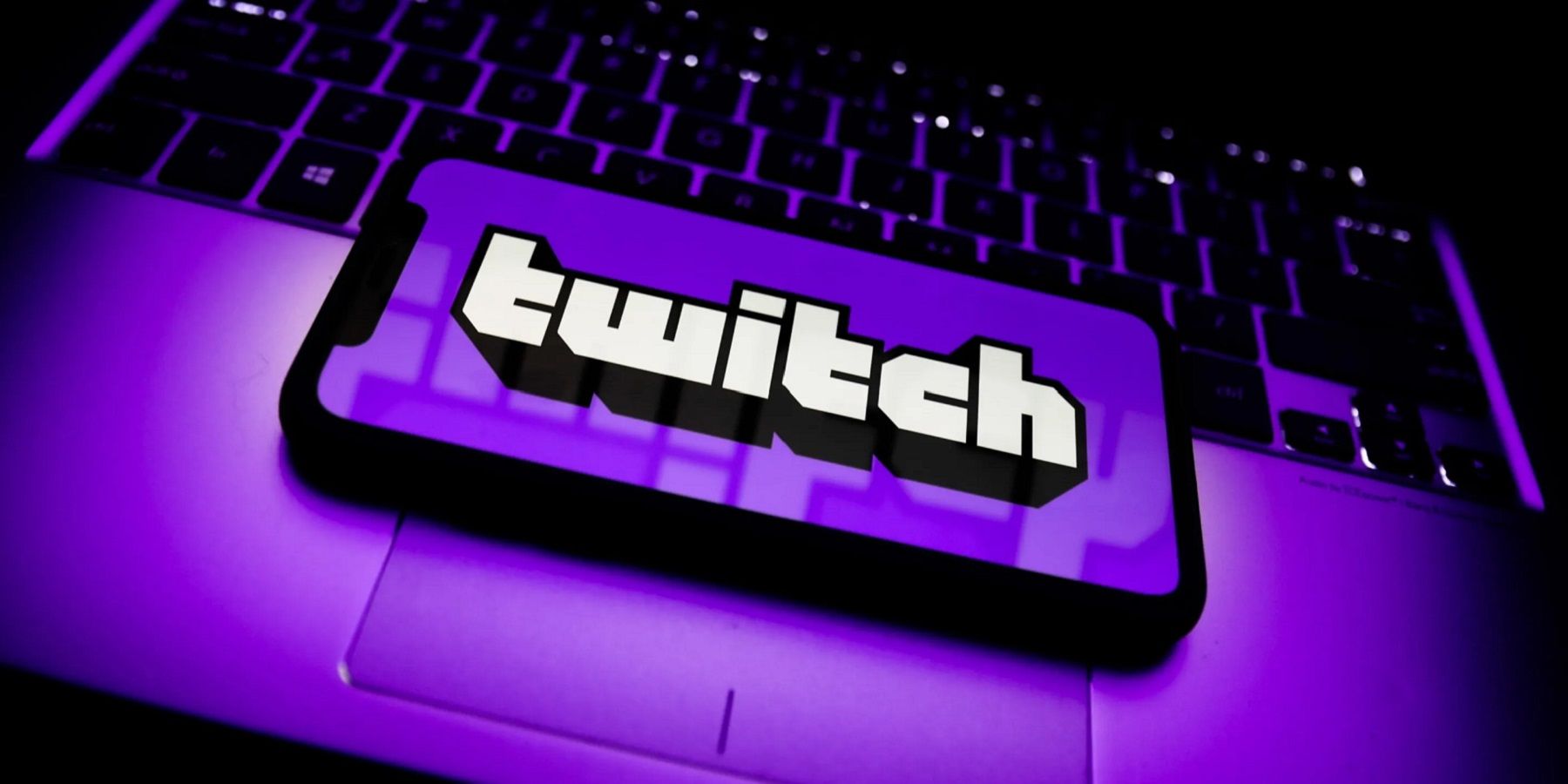 Телефон на ноутбуке с логотипом Twitch и фиолетовым фоном на телефоне